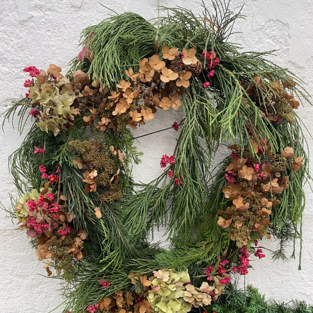 A festive hand-made wreath with berries, mistletoe and other seasonal foliage.